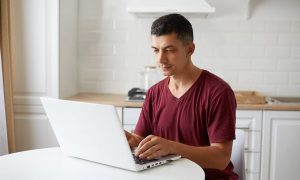 A man searching on his laptop who found a law firm due to local SEO for immigration lawyers.
